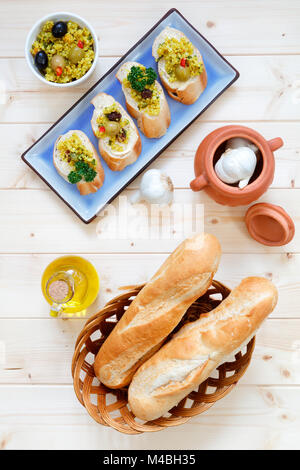 Brötchen im Korb mit Knoblauch und Olivenöl auf hellem Holz Tisch Stockfoto