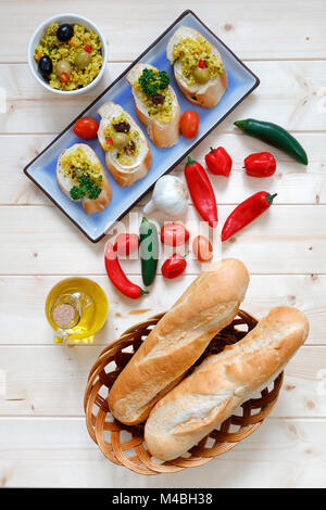Brötchen im Korb mit Knoblauch und Olivenöl auf hellem Holz Tisch Stockfoto