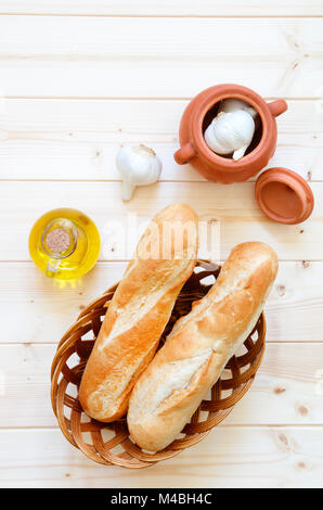 Brötchen im Korb mit Knoblauch und Olivenöl auf hellem Holz Tisch Stockfoto