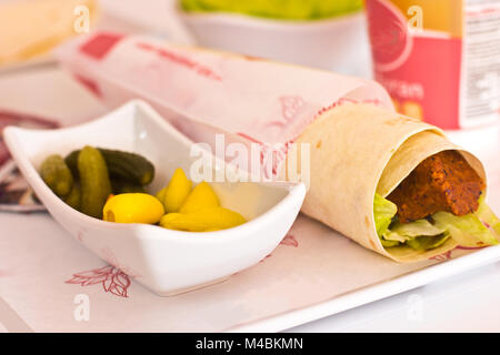 Traditionelle türkische Mahlzeit - Сig köfte-pikanten Koteletts aus Getreide mit den Gewürzen und Tomatenmark. Serviert mit dünnen Pita, Zitrone und grünem lettu Stockfoto