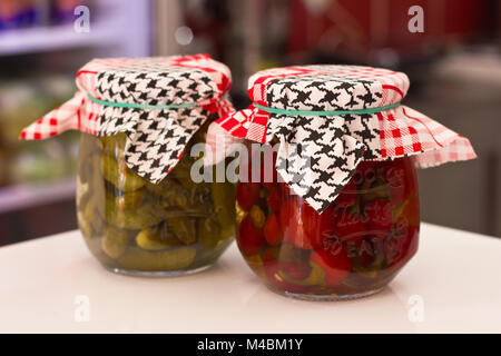Marinierte und eingelegtes Gemüse - Peperoni, Tomaten, Gurken in ein Glas Gläser mit Stoff bedeckt Stockfoto