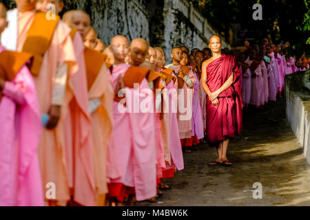 Buddhistische Nonnen in Warteschlange stehen in einer langen Reihe Spenden in ein Kloster zu erhalten Stockfoto