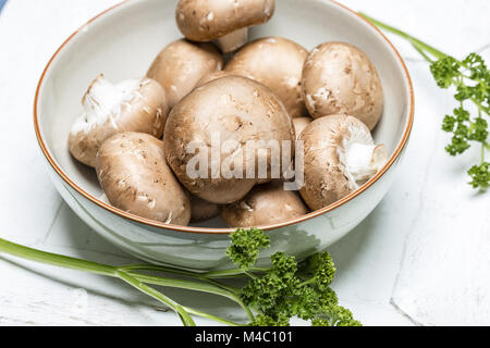 Braune Pilze in eine Schüssel geben und mit Petersilie - Close up Stockfoto