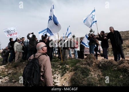 Jüdische Siedler und Aktivisten der rechten Organisation im Tirtzu halten israelische Flaggen, wenn sie israelischen linken Aktivisten der Peace Now-Bewegung gegenübertreten, die in Nativ Ha'avot offiziell gegen eine Ausweitung der jüdischen Siedlung Elazars im Siedlungskomplex Gush Etzion im Westjordanland demonstrieren. Am 15 Februar 2018. Die israelische Regierung versucht trotz des Urteils des Obersten Gerichtshofs, die Räumung einiger Häuser im Außenposten zu verschieben. Kredit: Eddie Gerald/Alamy Live News Stockfoto