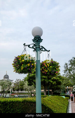 Reich verzierten Metall Lamp Post mit runden Kugel Licht auf der Oberseite mit zwei Körbe voller Blumen hängend auf beiden Seiten. - Disneyland Tokyo Stockfoto