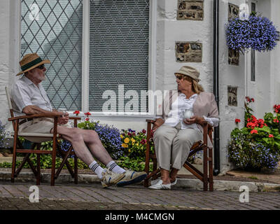 Ein älteres Paar entspannende auf Stühlen in einem Chat, Bier, Dorset, England, Großbritannien Stockfoto