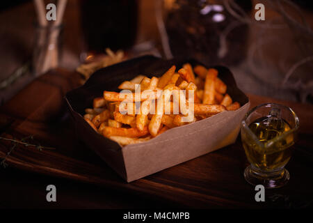 Pommes essen Foto. Street Food. Ungesunde lecker Gegrilltes, Pommes frites, hausgemachte Handwerk. Mit unscharfen Hintergrund Nahaufnahme. Rustikal farbe Stil. Stockfoto