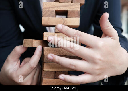 Geschäftsfrau Hand ziehen Sie den Holzklotz von der Tower. Wachstum, Risiko und Strategie im Business. Stockfoto