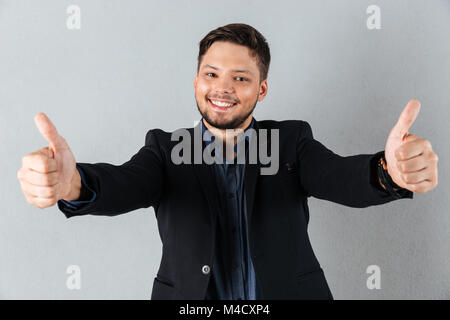 Portrait Of Happy Geschäftsmann mit zwei Daumen hoch isolierten über grauer Hintergrund Stockfoto