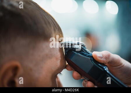 Mann bekommt einen coolen Haarschnitt im barbershop. Friseur macht den Schnitt mann Elektrorasierer. Men's Care Kopf. Soft Focus. Stockfoto