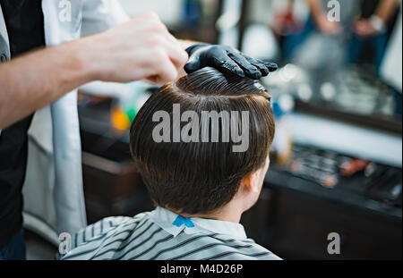 Mann bekommt einen coolen Haarschnitt im barbershop. Friseur macht den Schnitt mann Elektrorasierer. Men's Care Kopf. Soft Focus. Stockfoto