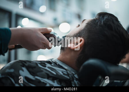 Friseur nivelliert sein Bart an den Clientcomputer für die Rasur. Der Client erhält die perfekte Form ihres Bartes. Soft Focus. Stockfoto