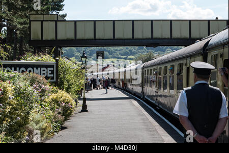 Zugbegleiter wartet als Reisende steigen und ein Erbe Dampfzug bei Winchcombe Station, Gloucesterhire verbinden. UK. Stockfoto