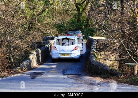 Autos passieren über die schmale, alte Neue Brücke über den Fluss Dart, Dartmoor, Devon, England Stockfoto