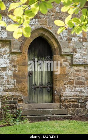 Eine gewölbte Tür an der Wand von St. Leonard's Kirche, Priors Marston, England, UK. Stockfoto