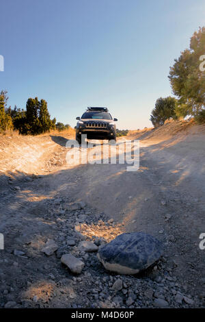 Ein grauer Jeep Cherokee mit einem Dachgepäckträger fahren hinunter eine narbige, Rocky Trail in Utah. Stockfoto