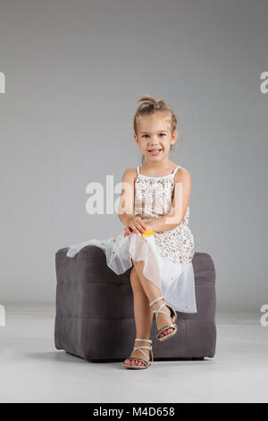 Happy kleines Mädchen sitzt auf einem Hocker in Studio Stockfoto