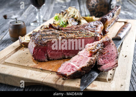 Grill Tomahawk Steak mit Pilzen auf Schneidebrett Stockfoto