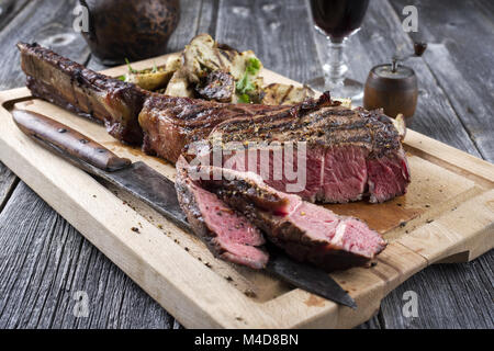 Grill Tomahawk Steak mit Pilzen auf Schneidebrett Stockfoto