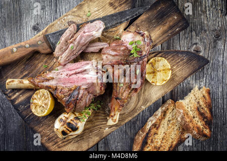 Grill Lamm Knuckles auf altem Schneidebrett Stockfoto