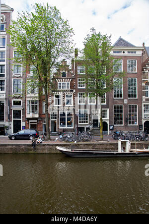 Typische Ansicht der Ferienwohnungen am Kanal mit Boot vor. In Amsterdam, Niederlande Stockfoto