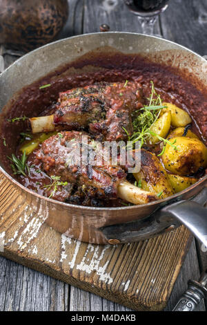 Lamm Knuckles mit Freid Kartoffeln in Burgund Soße in Kasserolle Stockfoto