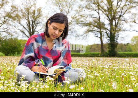 Frau schreiben in der Wiese mit Blumen Stockfoto