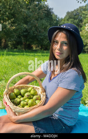 Porträt Frau hält Korb mit Birnen im Orchard Stockfoto