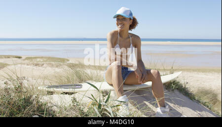 Gerne Frau auf einem Surfbrett Stockfoto