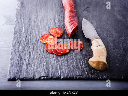 Spanische Chorizo mit einem Messer auf eine Steinplatte. Stockfoto