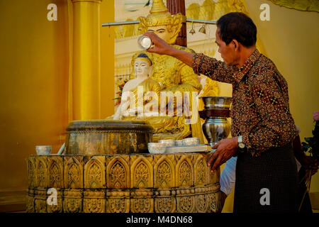 Mann vorformen Waschungen auf Statue an der Shwedagon Pagode in Yangon, Myanmar Stockfoto