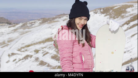 Lächelnde Frau mit Snowboard in den Bergen Stockfoto