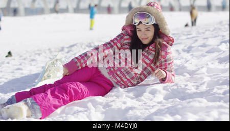 Junge Frau in rosa Schneeanzug mit skibrille Stockfoto