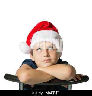 Der Junge in der rote Weihnachtsmann Mütze sieht nachdenklich bis Stockfoto