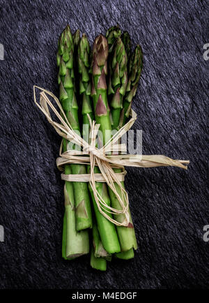 Bündel frische organische Spargel auf einem rustikalen Schiefer Hintergrund Stockfoto