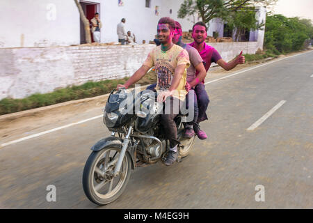 Barsana, Indien - 17. März 2016: Drei unbekannte indische Männer reiten ein Fahrrad mit pulverförmigen Farbstoffe während für Holi Festival in Indien abgedeckt Stockfoto