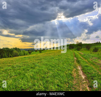 Sonnenstrahlen durch die Wolken schweben über die Wiese Stockfoto