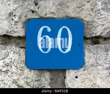 Blaue Straße Nummer 60 Zeichen auf einer Steinmauer Stockfoto