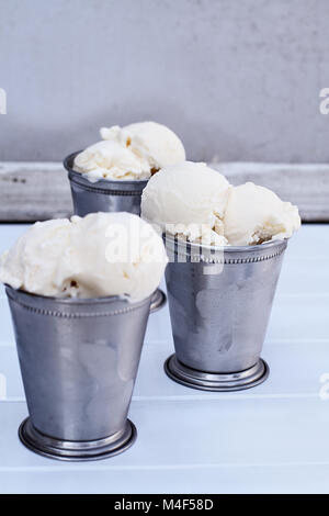 Frosty metall Cups mit Schaufeln von cremiger Vanille Eis gefüllt. Stockfoto