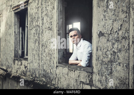 Schöner Mann schaut aus dem Fenster Stockfoto