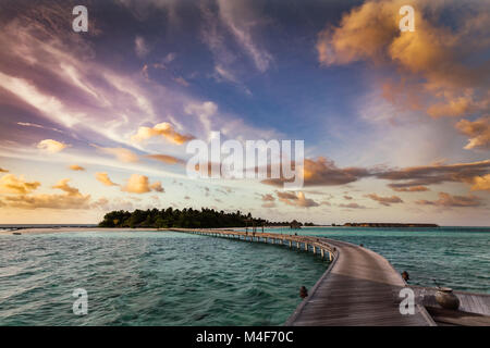 Holzsteg auf einer kleinen Insel auf den Malediven bei Sonnenuntergang Stockfoto