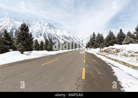 Leere asphaltierte Straße zwischen der schneebedeckte Berg Stockfoto