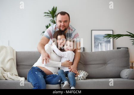 Bild der glücklichen Familie mit Sohn auf grau Sofa im Zimmer Stockfoto