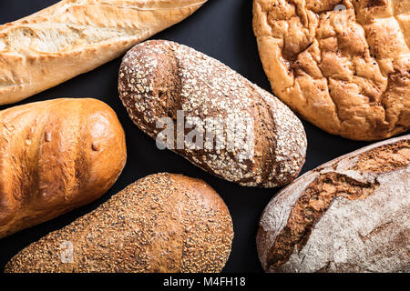 Vielzahl von frisch gebackenem Brot auf schwarzem Hintergrund Stockfoto