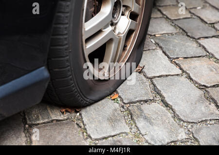 Nahaufnahme eines beschädigten Reifen eines Pkw auf die Straße. Stockfoto