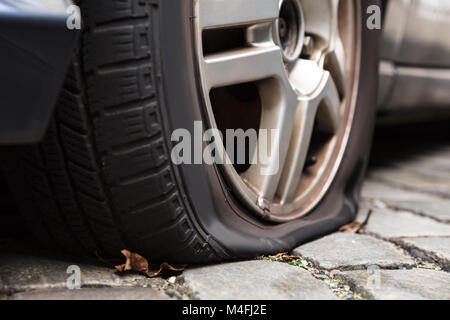 Nahaufnahme eines beschädigten Reifen eines Pkw auf die Straße. Stockfoto