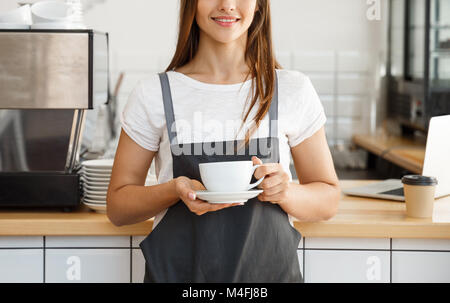 Kaffee Business Concept-kaukasischen Frauen Kaffee beim Stehen in der Coffee Shop. Fokus auf weibliche Hände eine Tasse Kaffee. Stockfoto