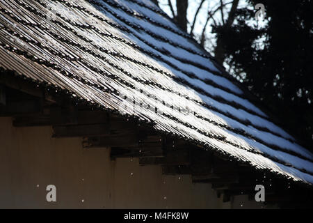 Wasser tropft aus der Traufe eines alten Haus im Dorf an einem sonnigen Wintertag Stockfoto
