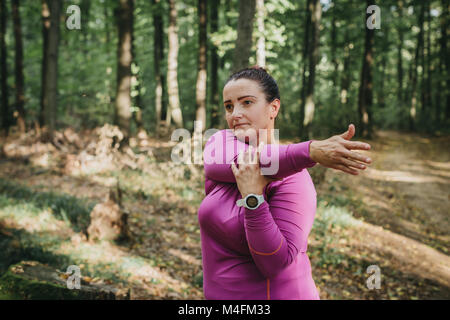 Portrait einer weiblichen Jogger zu einem Jog bereit und einige Strecken im Wald. Stockfoto