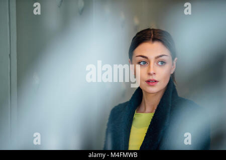 Geschäftsfrau steht in ihren Arbeitsplatz, aus Ihrem Bürofenster. Stockfoto